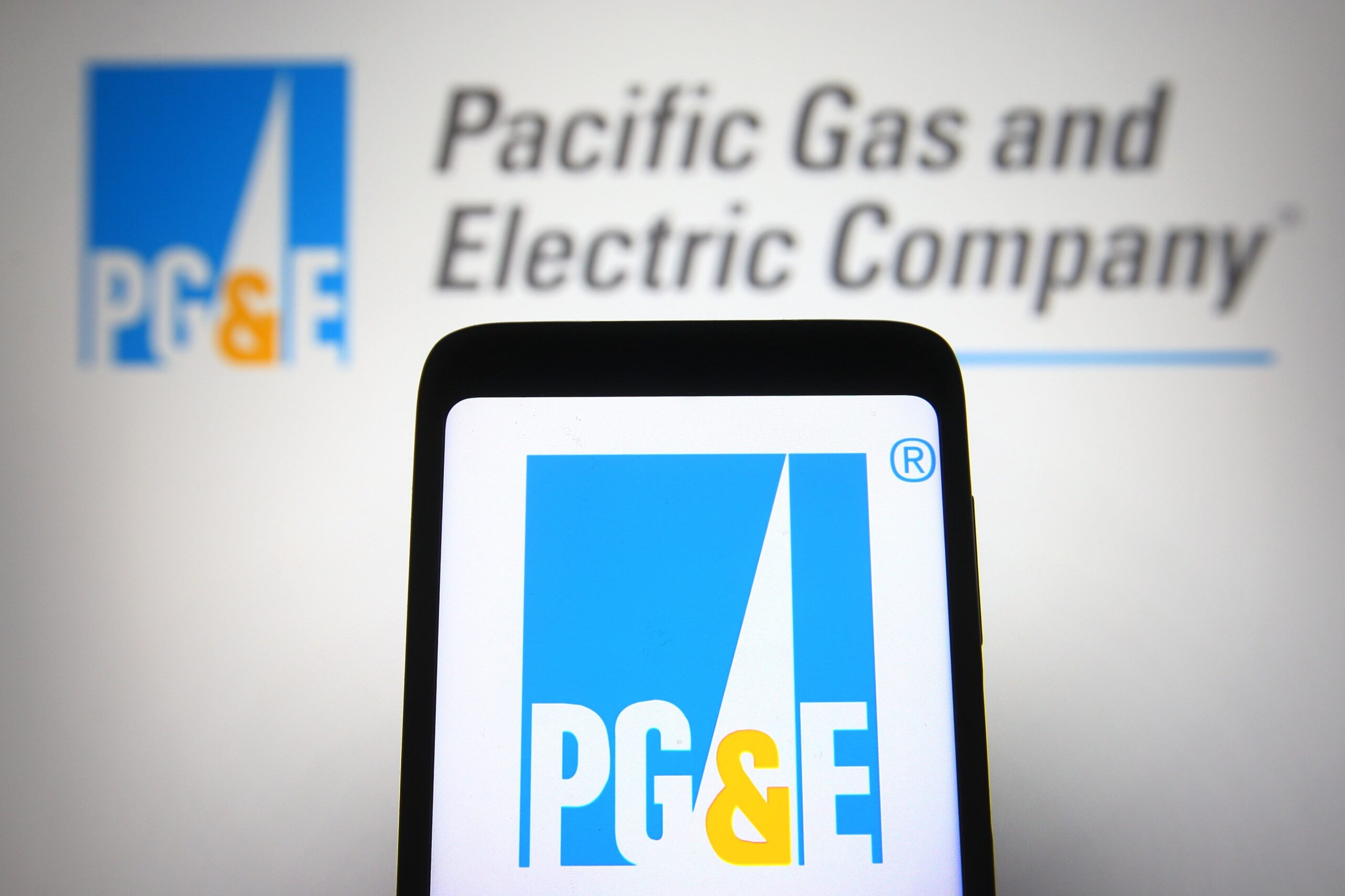 In this photo illustration, the Pacific Gas and Electric Company (PG&E) logo is seen on a smartphone and a pc screen.