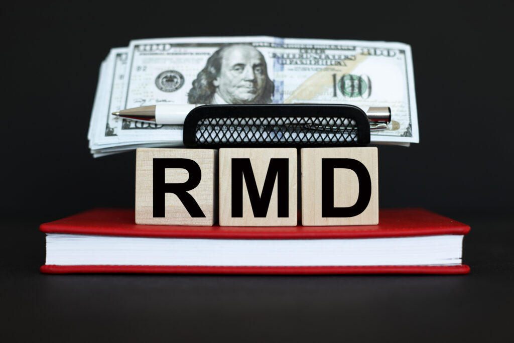 RMD Required Minimum Distribution. text on wooden cubes. On a black background. red notepad. Money